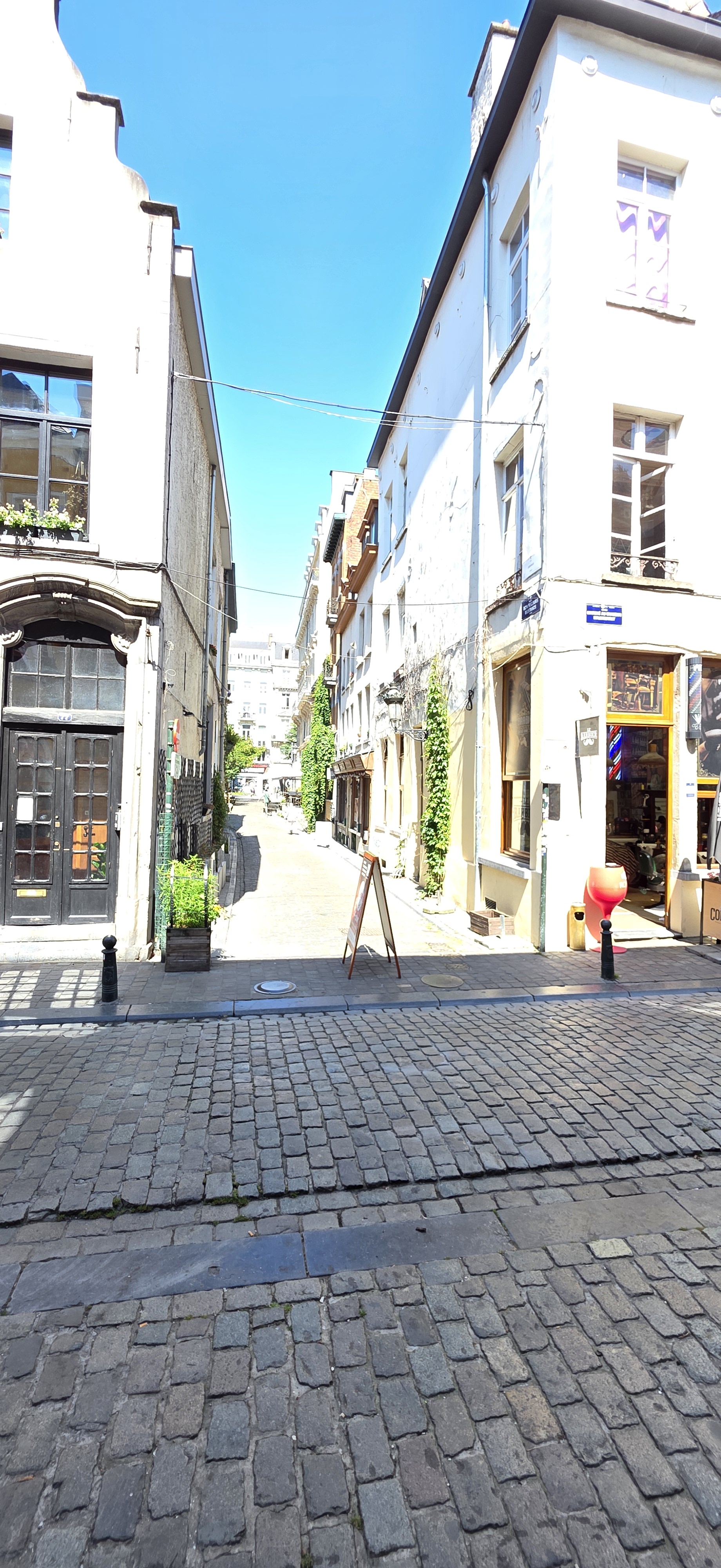 Narrow street of shops and cafes in central Brussels on a bright summer day
